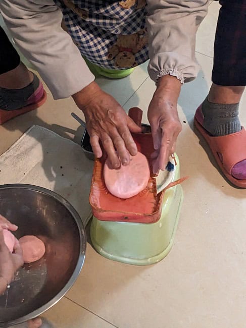 Making red sticky rice cakes with red bean paste inside
